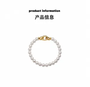Macro detail of round white pearl bracelet featuring a gold interlocking buckle with crystals