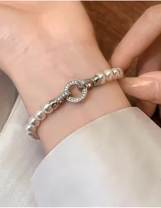 Detailed close-up of white round pearl bracelet with sparkling diamond-set clasp on wrist