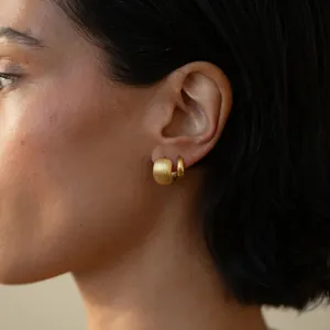 Set di orecchini a cerchio in oro spazzolato minimalisti su modella con finitura opaca