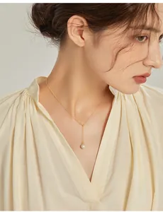 Detail of elegant gold Y-shaped necklace with single pearl pendant on woman neck