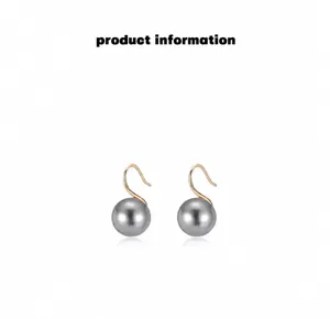 Macro detail of high-quality round gray pearl earrings with elegant golden hook design