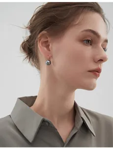 Detailed view of grey round pearl drop earrings with elegant gold hooks on a model