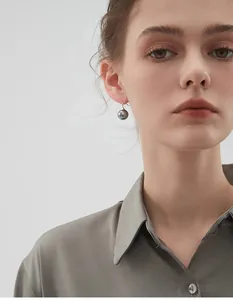 Close-up of elegant grey pearl earrings with gold hooks worn by a model in a minimal style