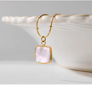 Primer plano de un collar dorado vintage con colgante cuadrado de nácar irisado