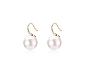 Detailed macro view of elegant round gray pearls on gold S-shaped dangle earring hooks