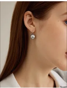 Close-up of elegant grey pearl drop earrings worn by a model for a modern look