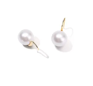 Close-up of elegant round pearl drop earrings with polished gold hooks on white background