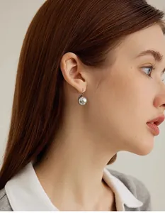 Close-up of S925 silver hook earrings featuring round metallic grey pearls on a model