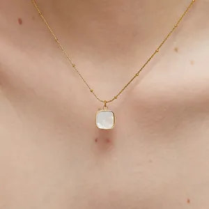 Collar vintage dorado con colgante cuadrado de nácar blanco usado por una modelo