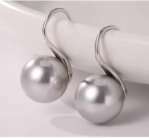 Detailed view of silver S-shape hook earrings with large metallic grey round pearls