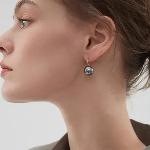 Elegant grey pearl earrings with golden hooks worn by a model in a minimalist style