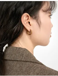 Detail of caramel brown enamel hoop earring on model with elegant gold-tone metal base