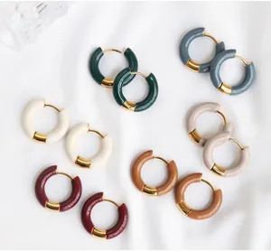 Close-up of colorful enamel hoop earrings set with gold-plated hinges on white fabric