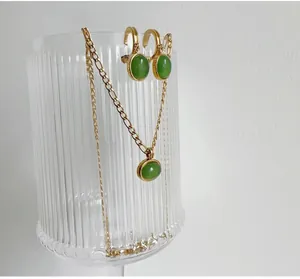 Macro view of gold-plated jewelry set featuring green aventurine pendants and earrings
