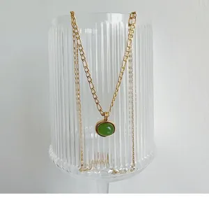Detail of green aventurine pendant necklace on a textured glass in a minimalist setup