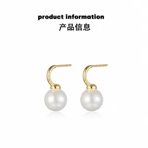Detailed view of round white pearls on gold C-shaped hooks with a polished mirror finish
