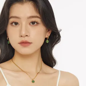 Elegant gold necklace and earrings set with green aventurine stones on a female model