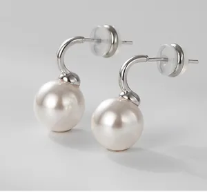 Detailed macro shot of round white pearl earrings with silver metal hooks and clear backs