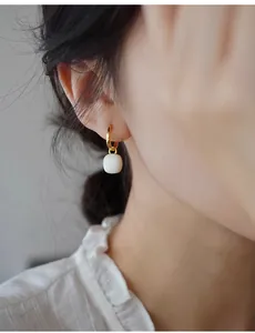 Detailsicht eleganter weißer quadratischer Ohrhänger, getragen von einem Model