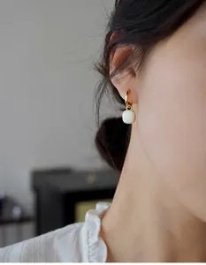 Nahaufnahme französischer Vintage-Ohrringe mit weißem Emaille-Anhänger und goldenen Ringen