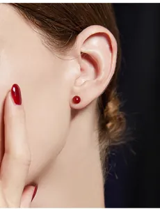 Primo piano di una modella che indossa un piccolo orecchino a perno in agata rossa