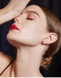 Primo piano dell'elegante piccolo orecchino a bottone in agata rossa lobo dell'orecchio