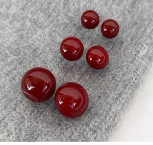 Gros plan de boucles d'oreilles perles rouge foncé sur fond en peluche grise