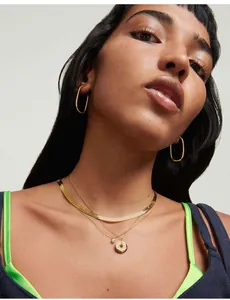 Detailaufnahme der flachen Gold-Schlangenkette und minimalistischer ovaler Ohrringe