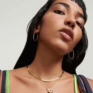 Flache goldene Schlangenkette im Set mit Layering-Anhängern für einen modernen Look