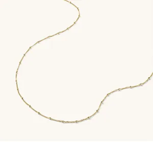 Detail of 18K gold-plated beaded chain showing delicate metal beads and polished finish