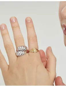 Detail of stacked gold butterfly signet ring and silver croissant dome band on finger