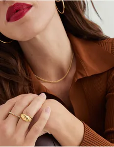 Detail shot of golden croissant ring and minimalist jewelry set on elegant model