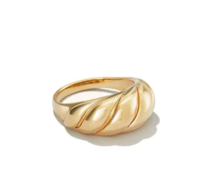 Detailed close-up of a high-polished golden croissant ring with a spiral ribbed texture