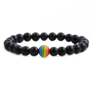 Macro shot of dark blue goldstone bracelet with a rainbow striped bead on white background