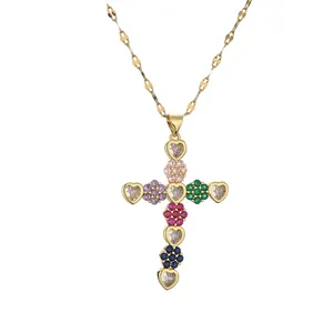 Collana a croce dorata con zirconi colorati a forma di cuore e fiori su bianco