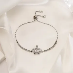 Detail of adjustable silver crown bracelet with shimmering cubic zirconia on white silk