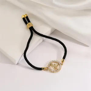 Detail of adjustable black woven tree of life bracelet with gold angel and zircon halo