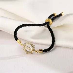 Detail of adjustable black woven bracelet with gold sun-shaped MOM charm and zircons