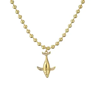 Collar de bolas doradas con colgante de ballena y detalles de cristal sobre fondo blanco puro