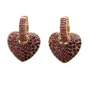Boucles d'oreilles cœur dorées ornées de zircons magenta sur fond blanc immaculé