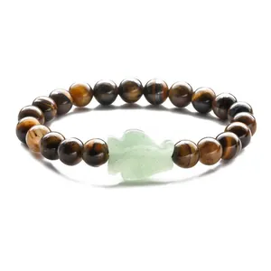 Brown tiger eye beaded bracelet with a light green carved jade charm on white background