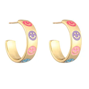 Gouden C-vormige oorbellen met kleurrijke emaille smileys op een witte achtergrond