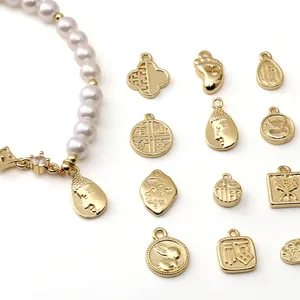 Dettaglio del bracciale di perle DIY con vari ciondoli portafortuna placcati in oro