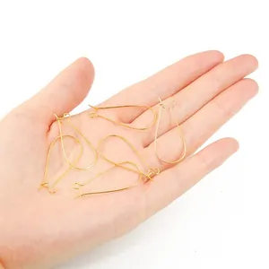 Set of five gold U-shaped earring hooks for DIY jewelry making held in hand for scale