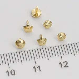 Macro shot of gold-plated 14K pendant connectors and jewelry parts with metric ruler
