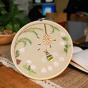 Close-up of handmade honey bee and daisy floral embroidery on bamboo hoop frame