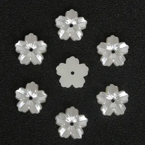 Primer plano de siete cuentas de flor de cerezo blanco crema con agujeros centrales en negro