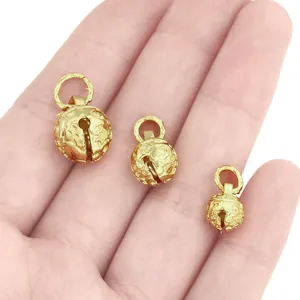 Golden hollow tiger head bells in three sizes shown on palm for DIY jewelry crafts