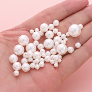 Main tenant des perles d'imitation rondes blanches avec trous pour bijoux DIY