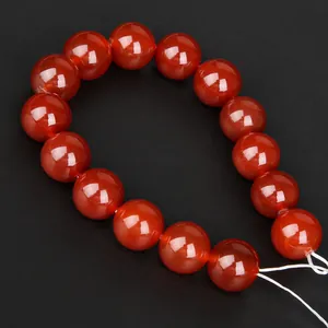 Armband mit 14 polierten roten Karneol-Perlen auf elastischem Band vor schwarzem Grund